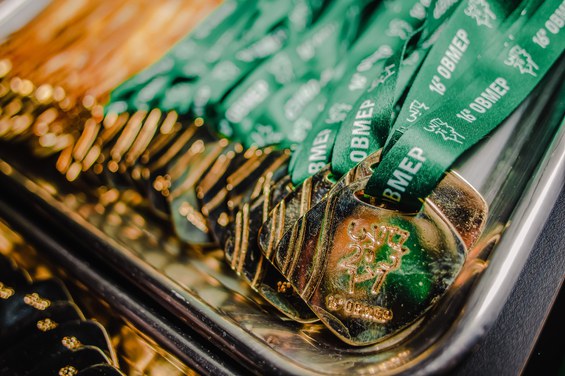 Imagem contendo várias medalhas de ouro da OBMEP dispostas em uma bandeja de prata